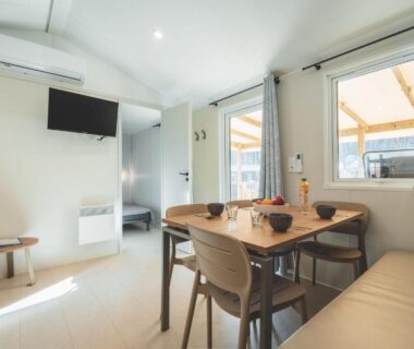 Intérieur de mobil-home avec coin repas et télévision dans le Camping Le Malazéou Wellness Sport Camping