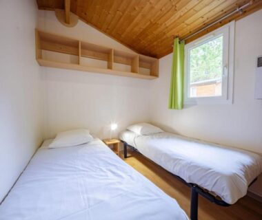 Chambre avec deux lits simples et plafond en bois au Camping Le Malazéou Wellness Sport Camping