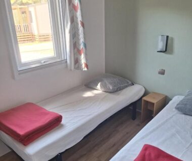 Chambre avec deux lits et couvertures rouges au Camping Le Mas