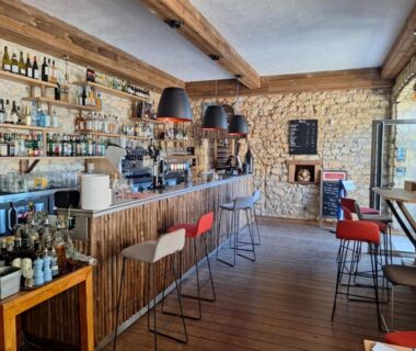 Bar intérieur en pierre avec comptoir et tabourets au camping Le Mas