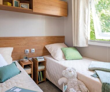 Chambre avec deux lits et fenêtre dans l'hébergement du Camping Le Mas de Reilhe