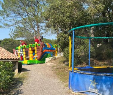 Allée avec trampoline et château gonflable au Camping Le Mas de Reilhe