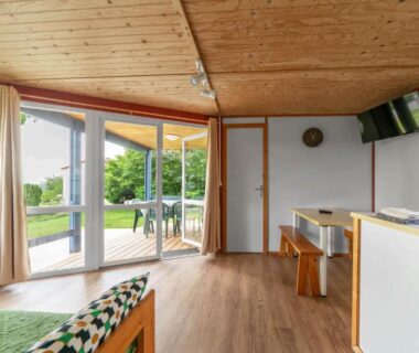 Terrasse et salon ouverts sur jardin et coin kitchenette au Camping Le Mont Libre