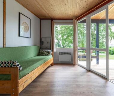 Salon avec baie vitrée et canapé dans le cottage du Camping Le Mont Libre
