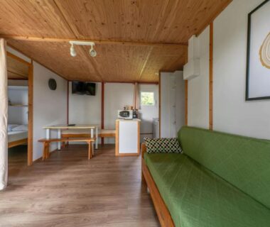 Séjour avec canapé et coin cuisine dans le cottage du Camping Le Mont Libre