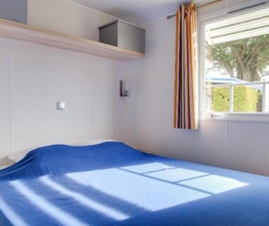 Intérieur de mobil-home avec lit double et fenêtre au Camping Le Moténo - Maeva
