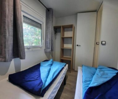Chambre avec deux lits et rangement dans le camping Le Moulin des Effres