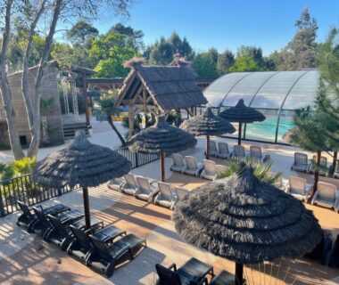 Terrasse piscine avec transats et parasols au Camping Le Paradis Carcans Lacanau