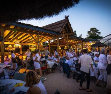Terrasse animée avec convives et éclairage chaleureux au Camping Le Paradis Carcans Lacanau