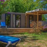 Terrasse en bois avec transats dans un cadre arboré au Camping Le Perpetuum
