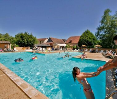 Piscine extérieure avec nageurs et transats au Camping Le Perpetuum