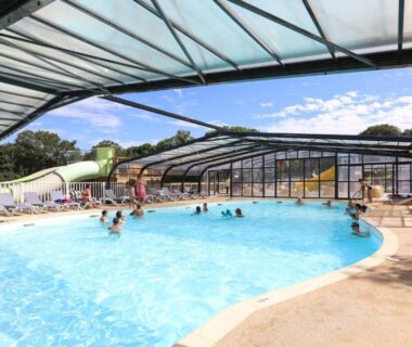 Piscine partiellement couverte avec toboggan et transats au Camping Le Petit Rocher