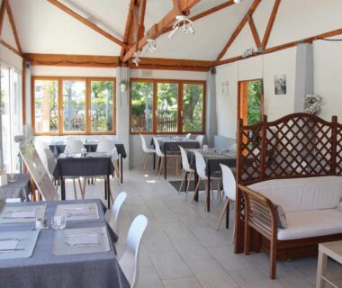 Salle à manger lumineuse avec tables et chaises dans le Camping Le Picard
