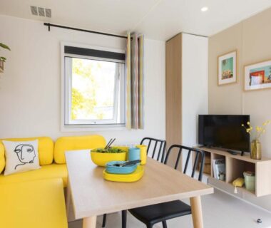 Séjour avec canapé jaune, table et télévision du Camping Le Picard