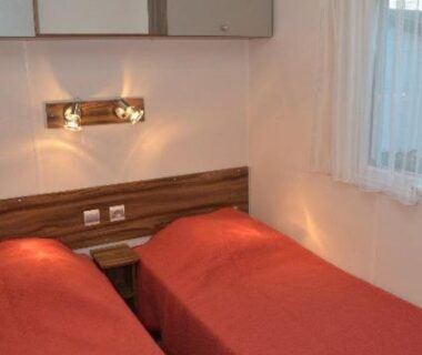 Chambre avec deux lits simples et voilage au Camping Le Puits Rochais