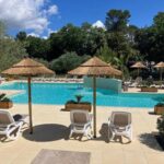 Piscine extérieure avec parasols et transats au Camping Le Relais de la bresque
