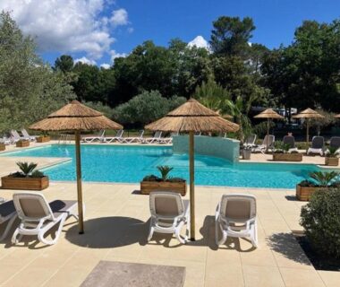 Piscine extérieure avec parasols et transats au Camping Le Relais de la bresque