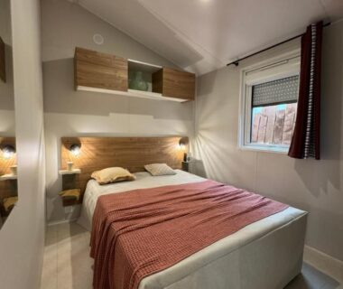 Chambre intérieure avec lit double, chevets et fenêtre au Camping Le Royan