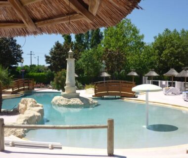 Piscine lagon avec pont et parasols au Camping Le Royan
