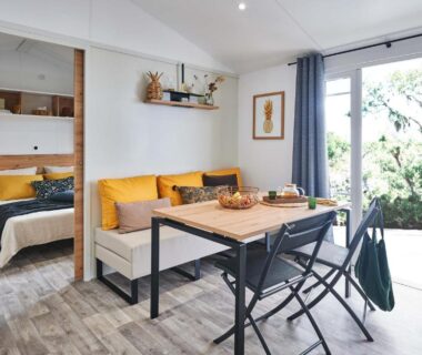 Séjour avec coin repas et lit ouvrant sur terrasse au Camping Le Royan