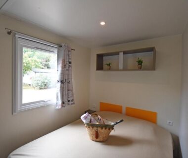 Chambre avec lit double, fenêtre et étagère au Camping Le Sagone