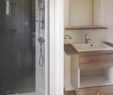 Salle de bain avec cabine de douche et lavabo au Camping Le Sagone