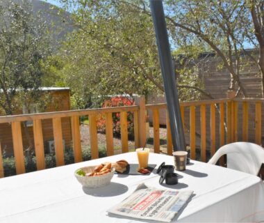 Terrasse en bois avec table petit déjeuner et chaises au Camping Le Sagone
