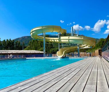 Piscine extérieure avec toboggan en spirale et ponton en bois au Camping Le Sagone