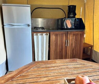 Coin cuisine avec réfrigérateur plaque de cuisson et table en bois au Camping Le Sans Souci