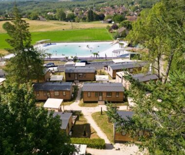 Vue aérienne de la piscine et des lodges en bois dans la campagne du Lot au Camping Le Sequoia