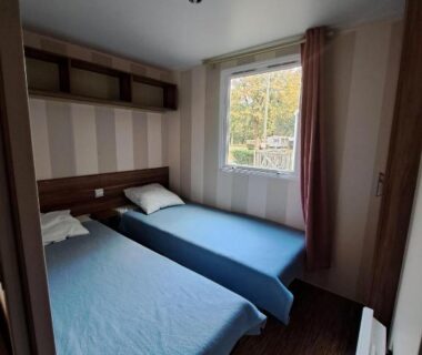 Chambre avec deux lits et fenêtre au Camping Le Soulhol