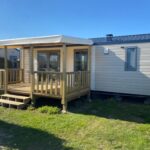 Mobil-home avec terrasse en bois sur pelouse au Camping Le Tarteron