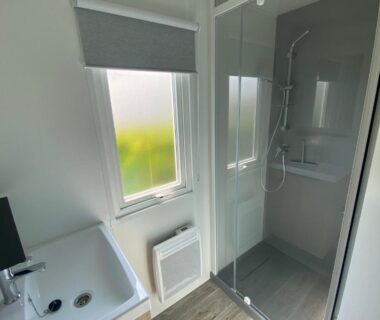 Salle de bain avec douche vitrée lavabo et fenêtre dans le Camping Le Tarteron