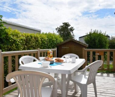 Terrasse en bois avec table et chaises sur emplacement de mobil-home au Camping Le Tarteron