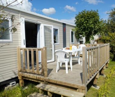 Terrasse en bois avec table et chaises blanches au camping Le Tarteron