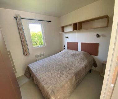 Chambre avec lit double et fenêtre au Camping Le Tarteron
