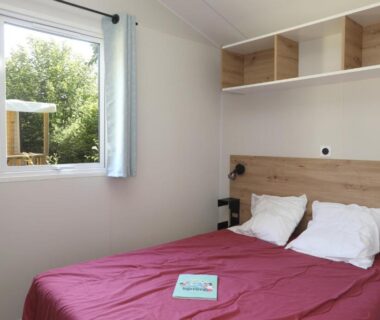 Chambre avec lit double et fenêtre au Camping Le Val de Trie