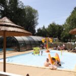 Piscine extérieure avec bassins pour enfants et parasols au Camping Le Val de Trie
