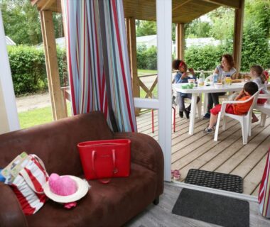 Terrasse couverte avec canapé et table à manger au Camping Le Val de Trie