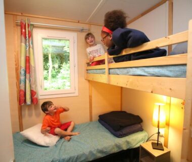Chambre avec lits superposés et enfants au Camping Le Val de Trie