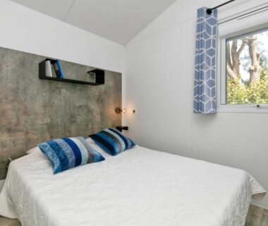 Chambre avec lit double et fenêtre au Camping Le Village de la Mer