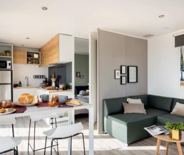 Séjour ouvert avec canapé coin repas et kitchenette dans le mobil home du Camping Le Walric