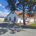 Entrée et bâtiment d'accueil sous arbre au Camping Les 2 Plages