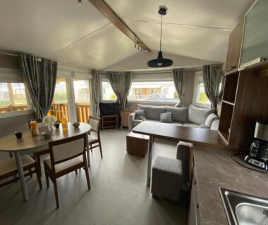 Intérieur de mobil-home avec salon canapé et kitchenette au Camping Les 2 Plages