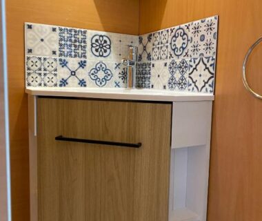 Coin salle de bain avec meuble en bois et crédence en faïence au Camping Les Amandiers