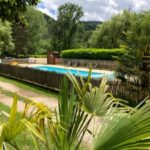 Piscine extérieure entourée de végétation au Camping Les Berges Du Doux
