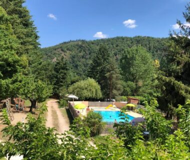 Piscine extérieure entourée de forêt au Camping Les Berges Du Doux