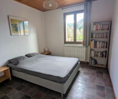 Chambre avec lit double et bibliothèque au Camping Les Berges Du Doux