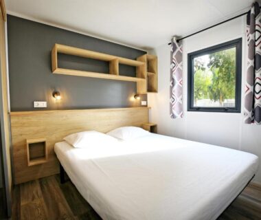 Chambre avec lit double et fenêtre au Camping Les Castors