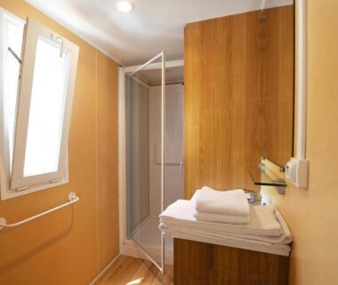 Salle d'eau avec cabine de douche et serviettes dans mobil-home au Camping Les Castors